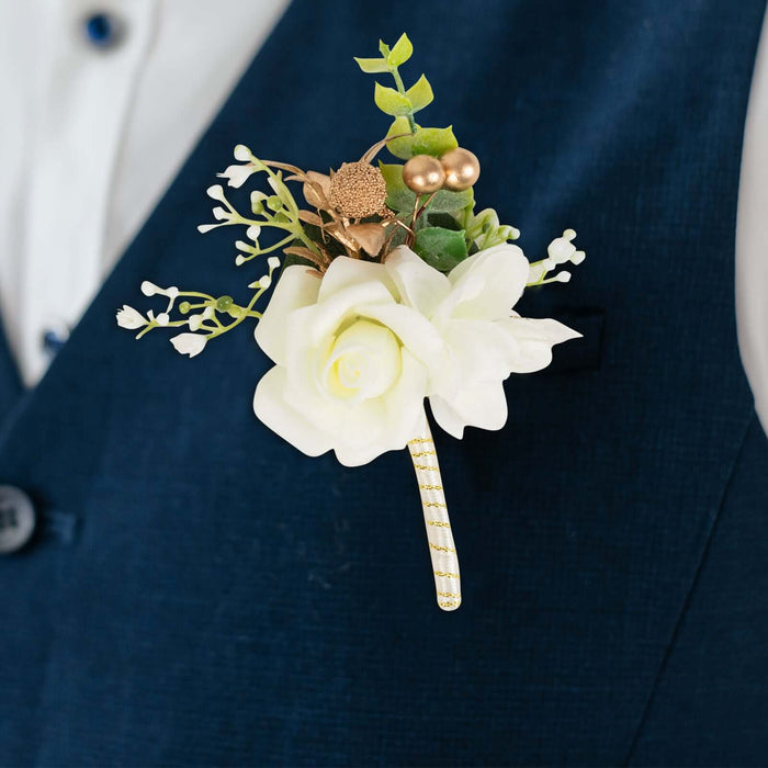 White rose boutonniere with greenery and gold accents on a blue suit.