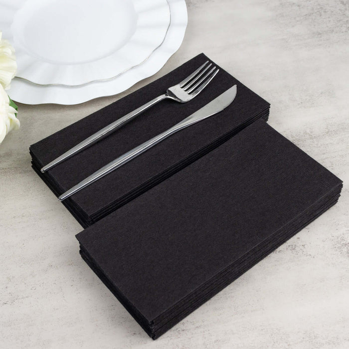 Black disposable napkins with silver cutlery on a table setting.
