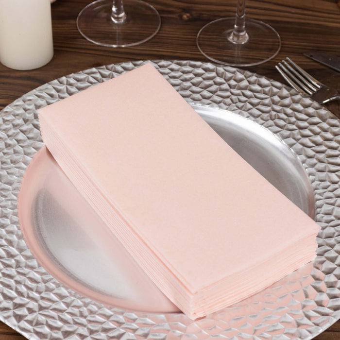Stack of pink dinner napkins on a decorative silver plate.
