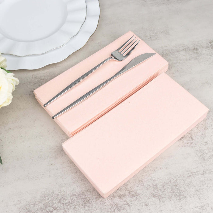 Pink napkins with a fork and knife on a light surface.