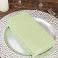 Stack of light green napkins on a decorative silver plate.