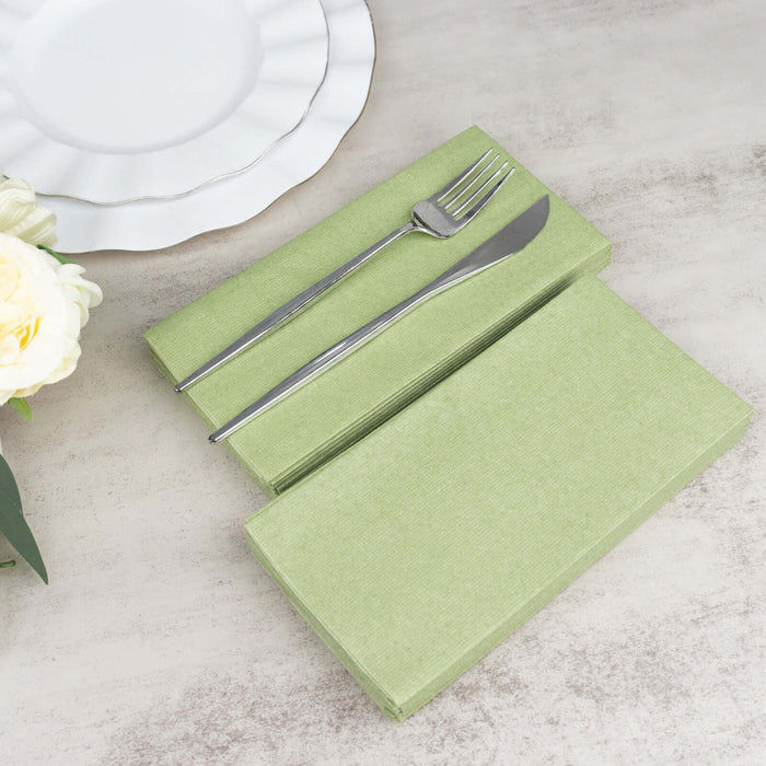 Green linen napkins with silver cutlery on a table setting.