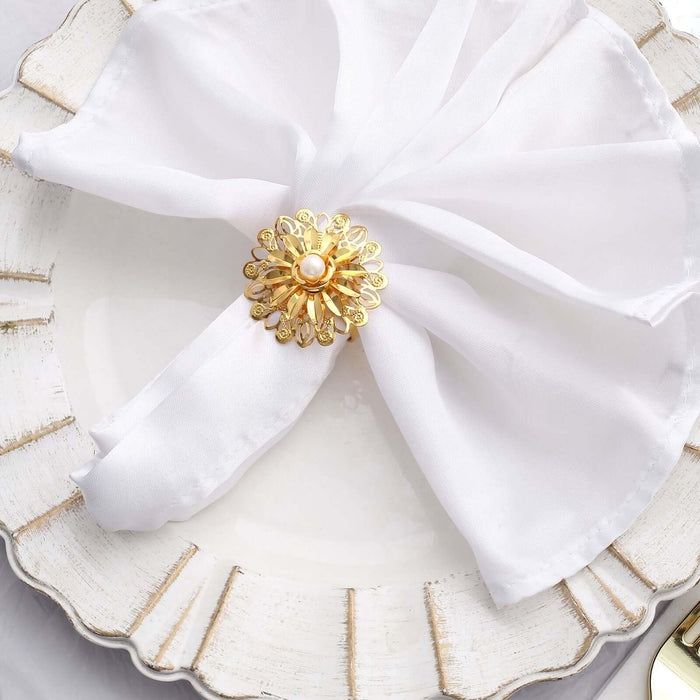 Gold flower napkin ring on a white plate with a sheer napkin.