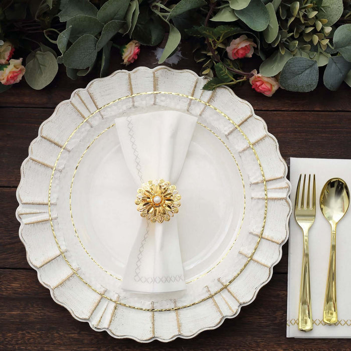 Elegant white plate with gold trim, napkin, and floral centerpiece on wooden table.