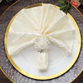 Elegant cream napkin with silver ring on a decorative plate.