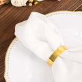Elegant white napkin wrapped with a gold napkin ring on a decorative plate.