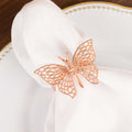 Rose gold butterfly napkin holder on a white napkin and plate.