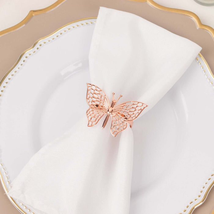 Rose gold butterfly napkin holder on a white napkin atop a decorative plate.