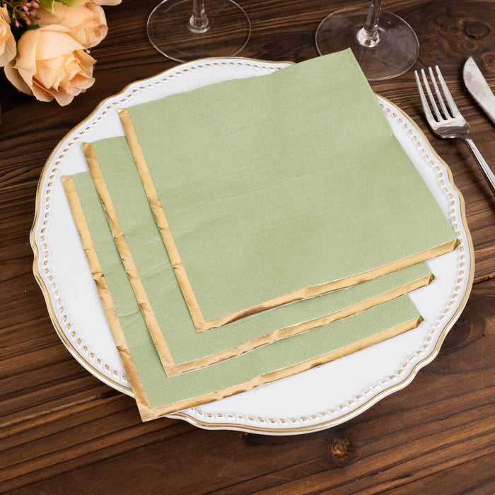 Green paper napkins with gold edges on an elegant white plate.