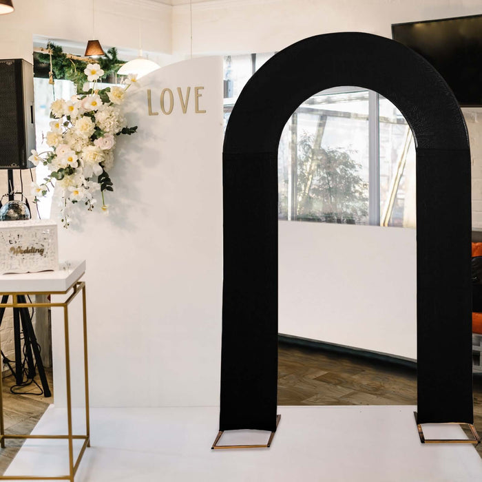 Black wedding arch with gold accents against a white backdrop.