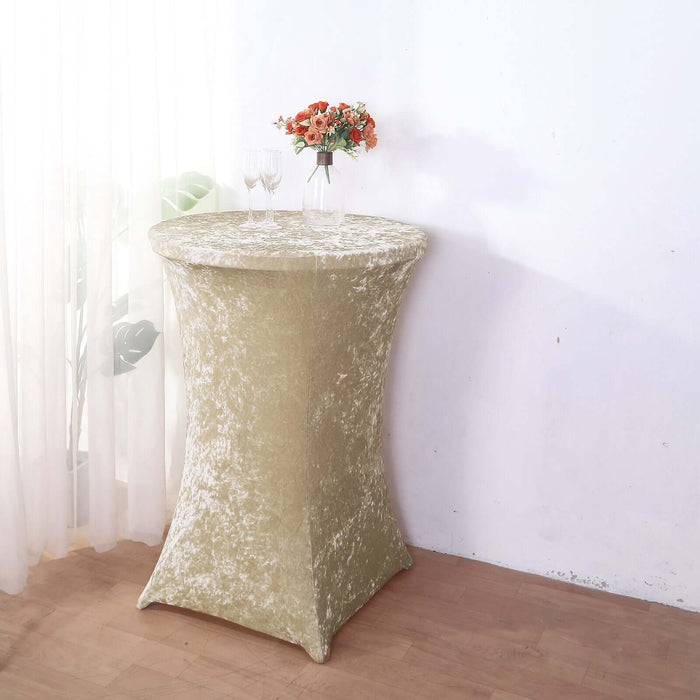 Elegant gold table cover draped over a round table with flowers and glasses.