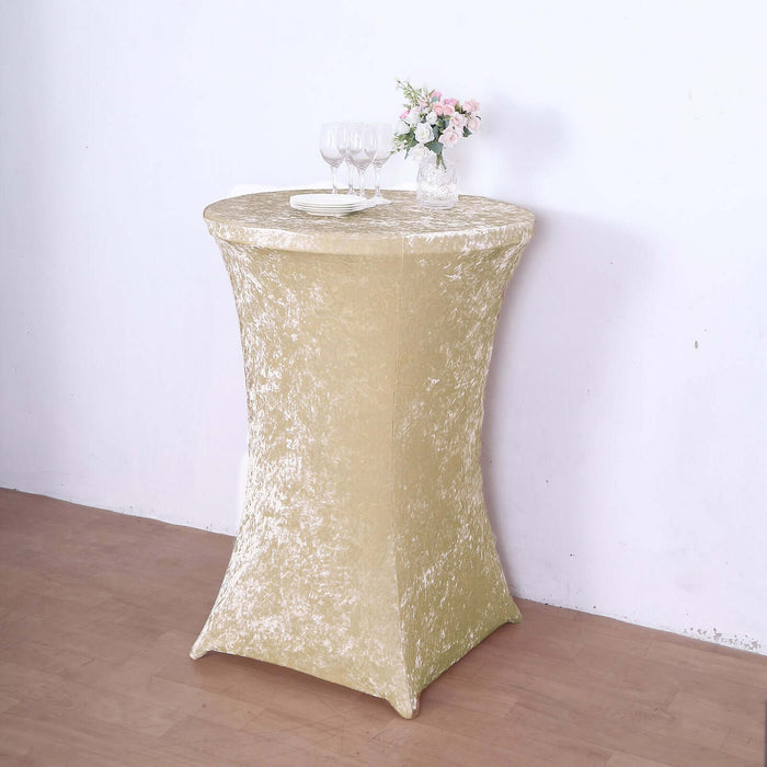 Gold stretch table cover on a round table with drinks and flowers.
