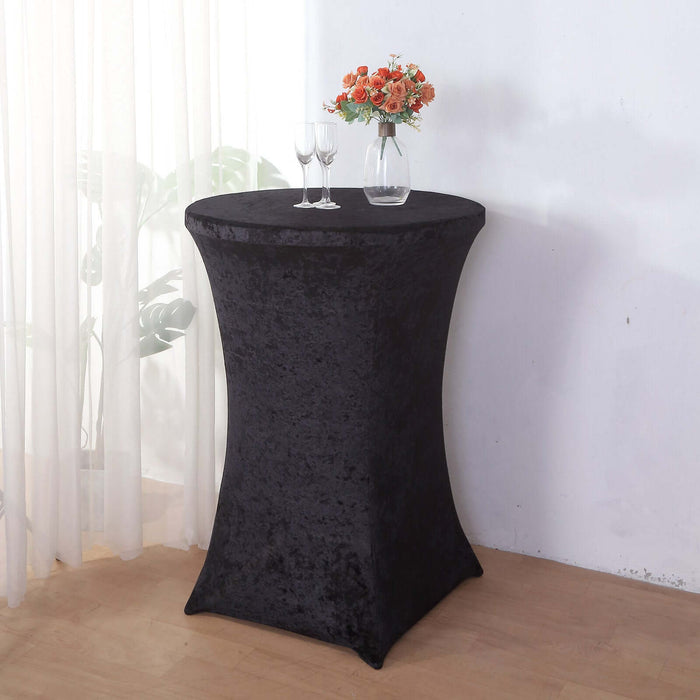 Black stretch table cover on a cocktail table with glasses and flowers.