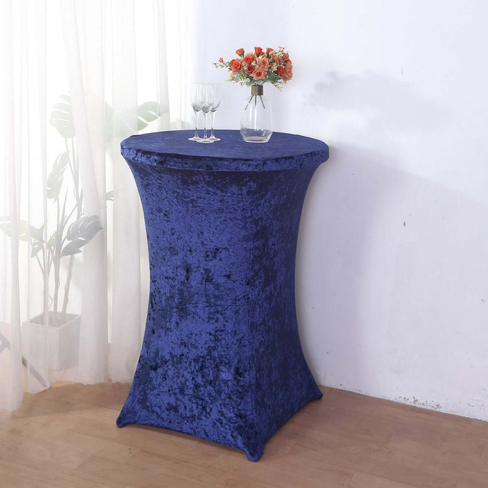 Navy blue table cover on a tall table with flowers and glasses in a bright setting.