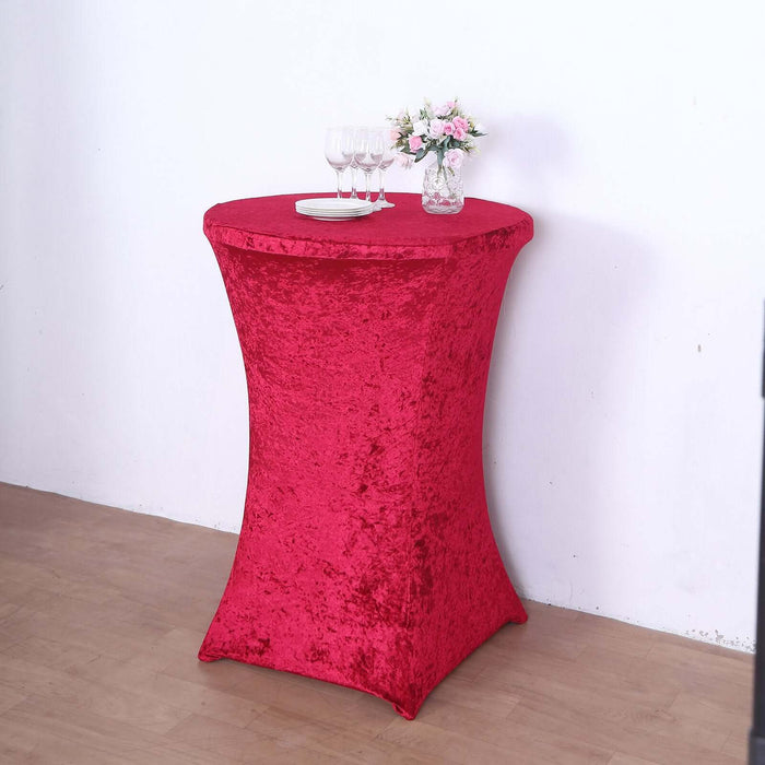 Red sequin table cover draped over a cocktail table with glasses and flowers.