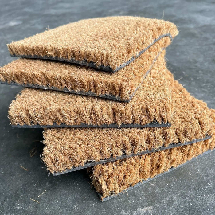 Stack of brown doormats on a dark surface
