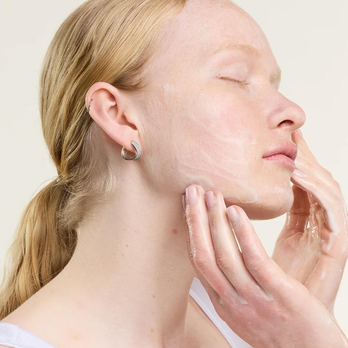 Woman touching her face with a neutral background.