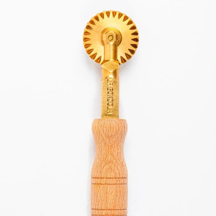Gold and wooden pasta cutter on a white background.