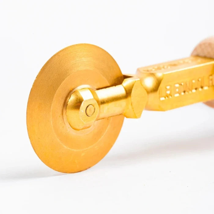 Close-up of a gold Pasta cutter wheel on a white background.