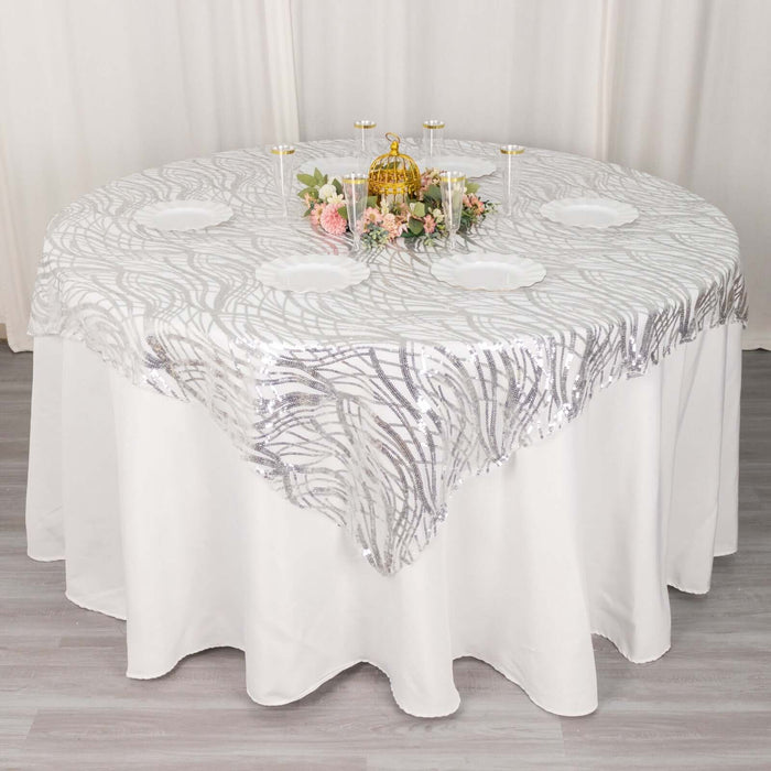Round table with a decorative silver sequin tablecloth and floral centerpiece.