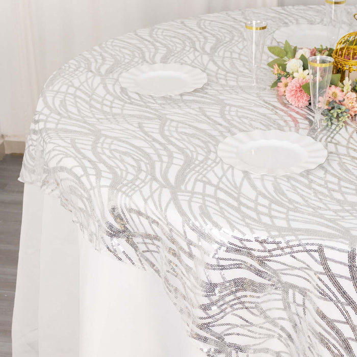 Elegant silver wave-patterned tablecloth on a round table with floral decor.