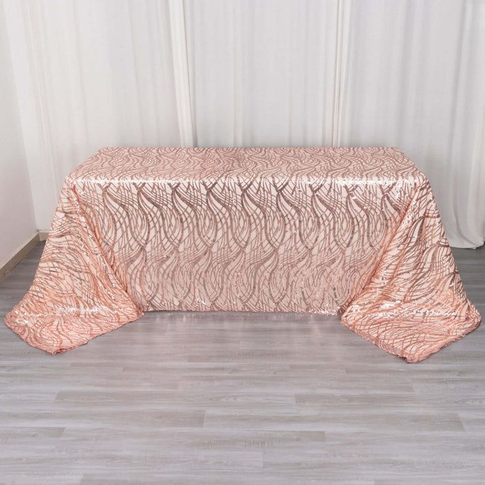 Rose gold sequin tablecloth with wavy pattern on a plain backdrop.