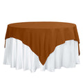 Brown tablecloth draped over a round table with white skirt.