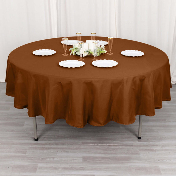 Brown round tablecloth draped over a table set for dining.