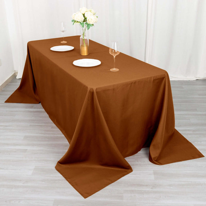 Brown tablecloth draped over a table set for dinner with plates and glasses.