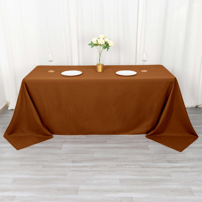 Brown tablecloth on a dining table set with plates and glasses.