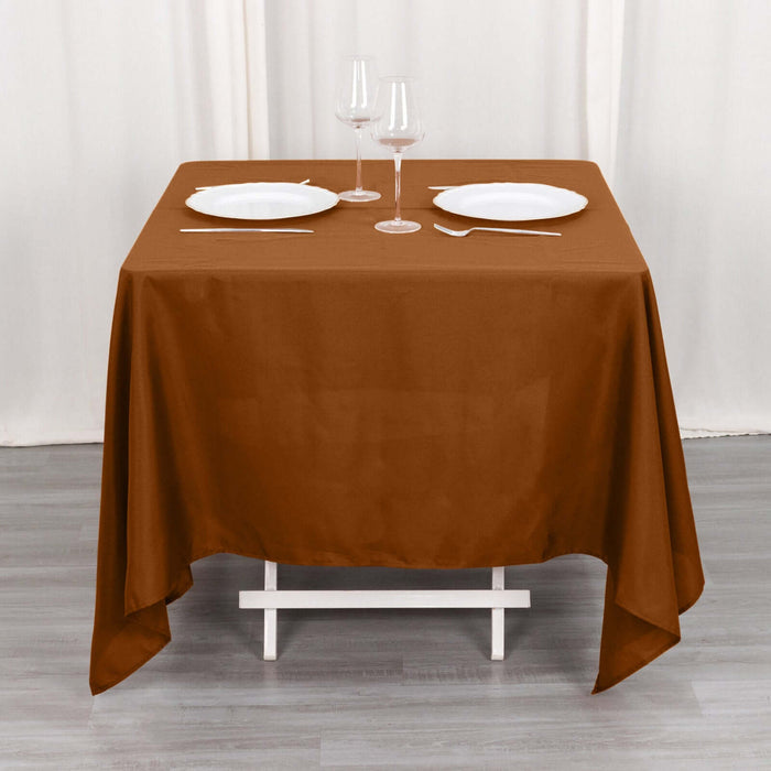 Brown tablecloth draped over a table set with plates and glasses.