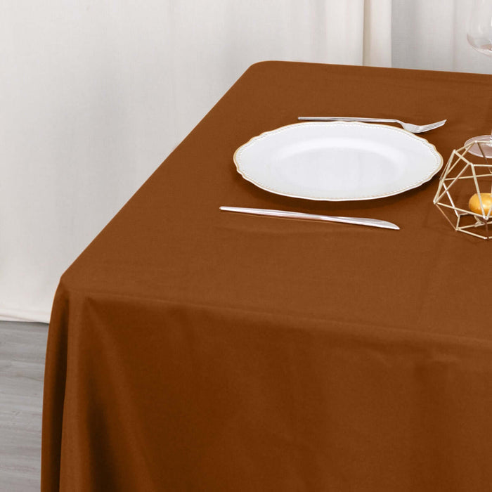 Brown tablecloth draped on a table with a white plate and decorative items