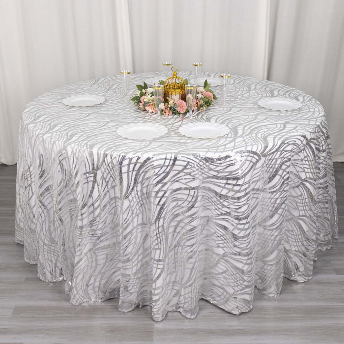Round table with elegant gray wavy patterned tablecloth and decorative centerpiece.