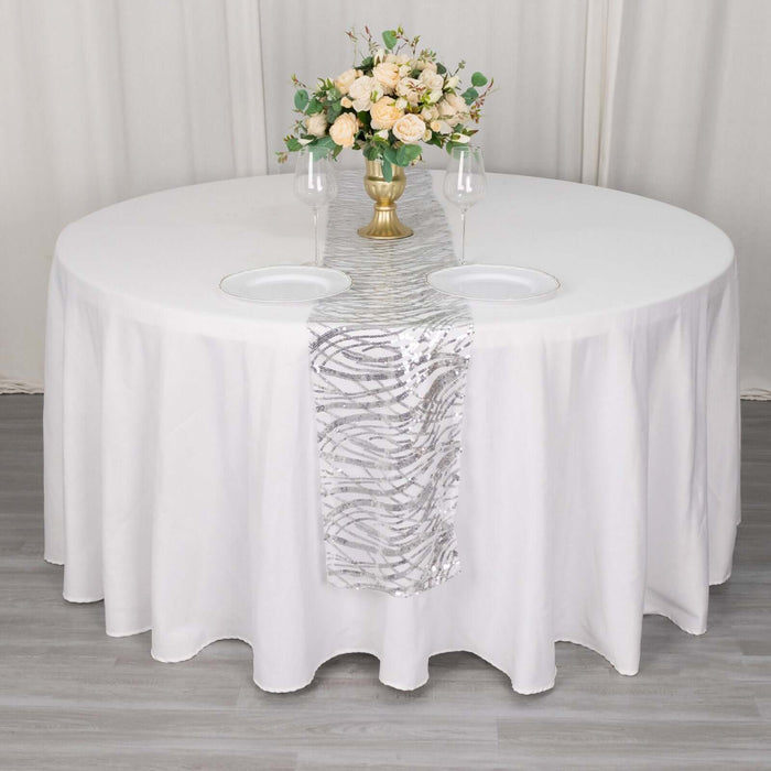 Elegant round table setup with floral centerpiece and silver runner.