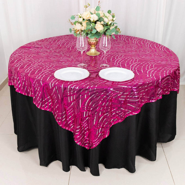 Round table with a pink and black tablecloth, set with plates and glasses.
