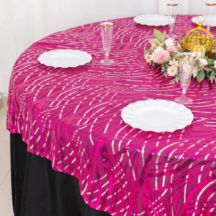 Round table with a vibrant pink tablecloth and elegant dining setup.