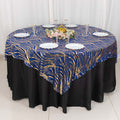 Elegant blue and gold patterned tablecloth on a round table with white plates.