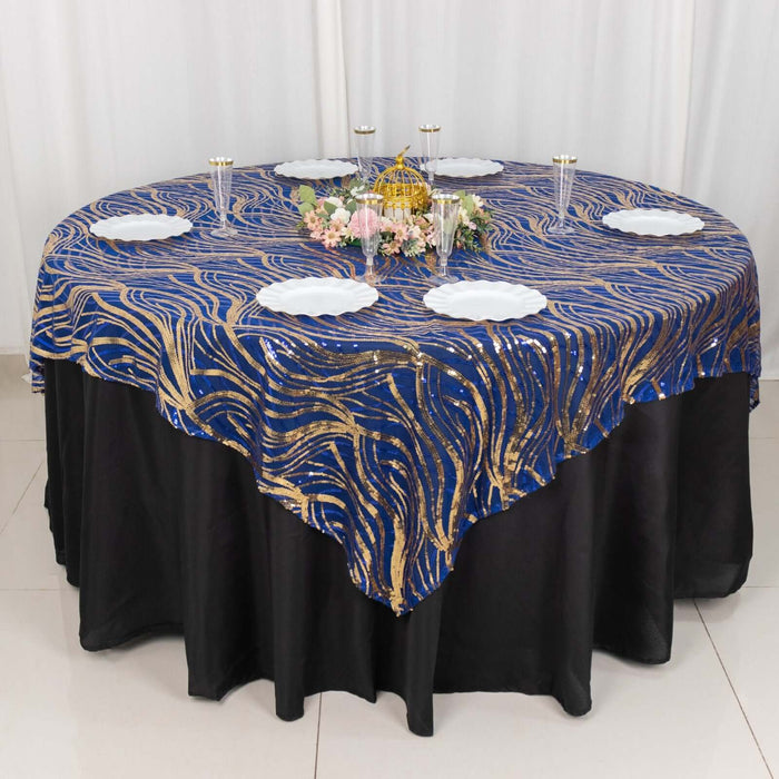 Elegant blue and gold patterned tablecloth on a round table with white plates.