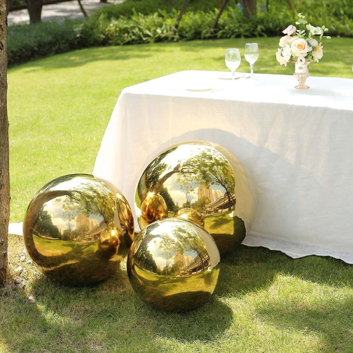 Gold decorative spheres on a garden lawn with a table and floral centerpiece.