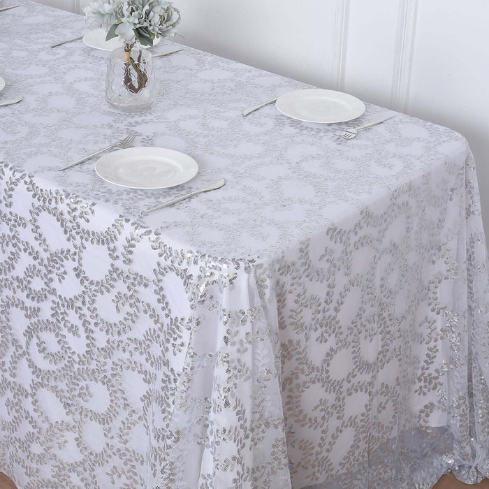 Elegant white tablecloth with silver floral pattern on a dining table.