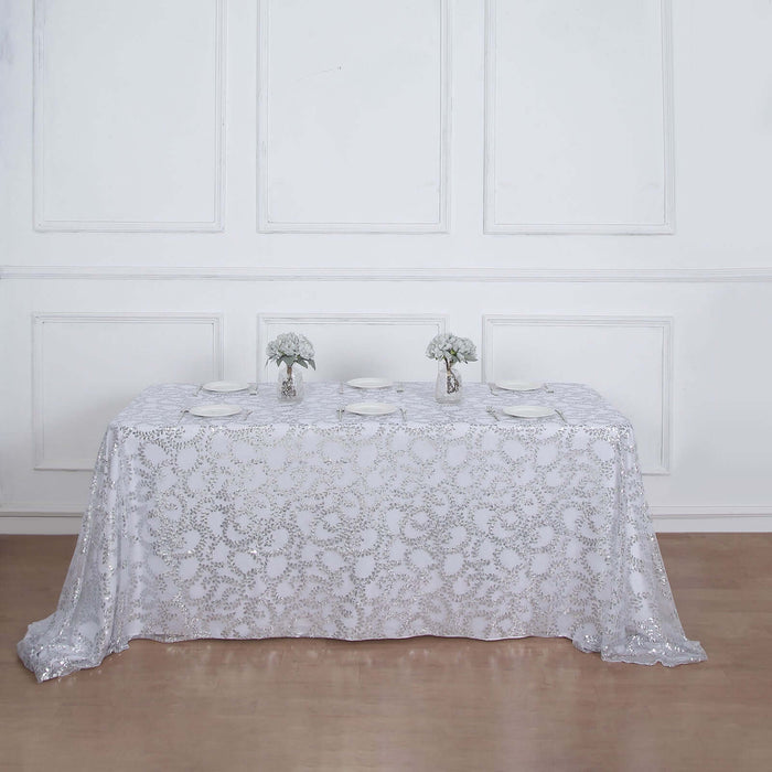 Elegant white lace tablecloth draped over a dining table with floral centerpieces.